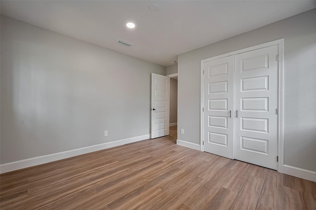unfurnished bedroom with visible vents, baseboards, light wood-style flooring, and a closet