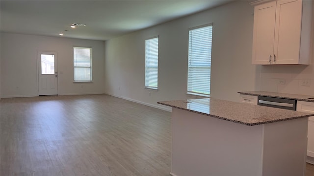 kitchen featuring light stone counters, white cabinetry, light wood-type flooring, and baseboards