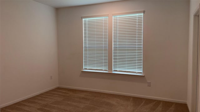 carpeted spare room featuring baseboards