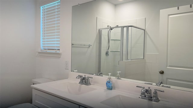 bathroom with toilet, double vanity, a sink, and a shower stall