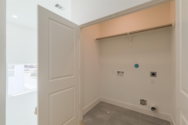 washroom with dark tile patterned flooring, hookup for an electric dryer, visible vents, and gas dryer hookup