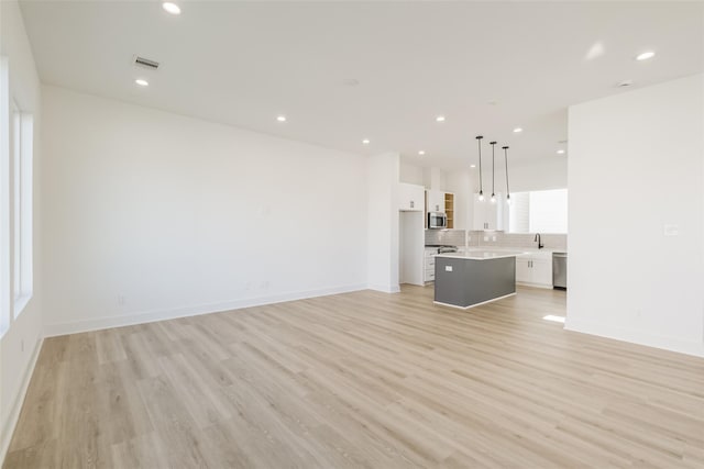 unfurnished living room featuring recessed lighting, baseboards, visible vents, and light wood-type flooring
