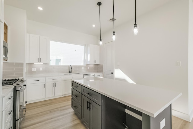 kitchen with light countertops, stainless steel appliances, a sink, and tasteful backsplash