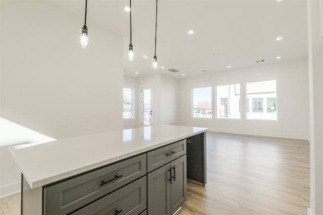 kitchen featuring a kitchen island, visible vents, gray cabinetry, light countertops, and light wood finished floors