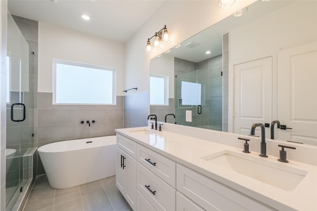 bathroom with a sink, tile patterned floors, a stall shower, and tile walls