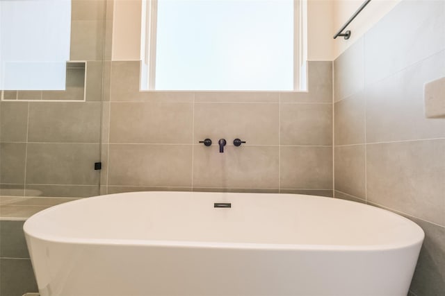 bathroom featuring tile walls and a soaking tub