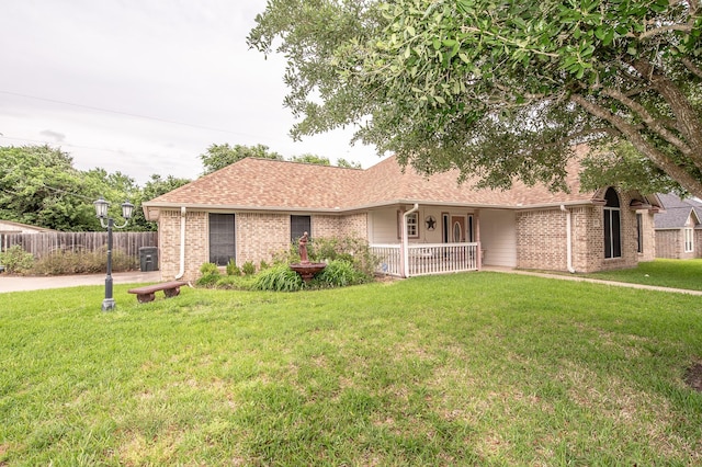 ranch-style home featuring covered porch, brick siding, fence, and a front lawn
