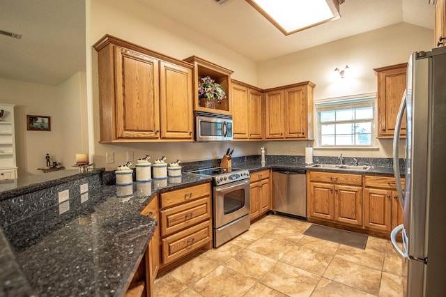 kitchen with appliances with stainless steel finishes, a sink, brown cabinetry, dark stone countertops, and visible vents