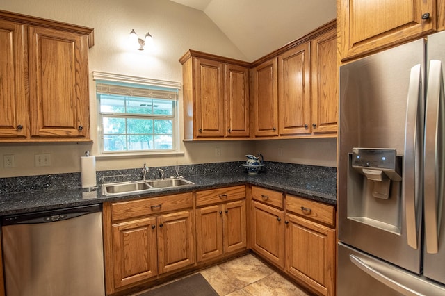 kitchen with brown cabinets, stainless steel appliances, a sink, and lofted ceiling