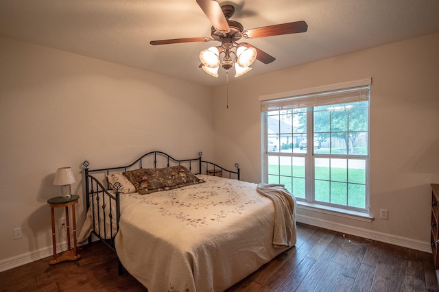 bedroom with baseboards, multiple windows, a ceiling fan, and dark wood-style flooring