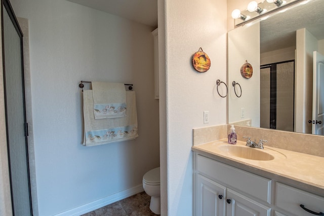 bathroom featuring vanity, tile patterned flooring, toilet, baseboards, and a shower stall