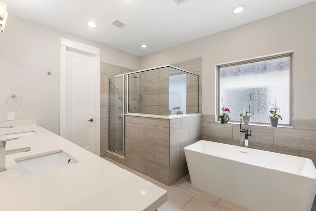 full bath with a freestanding tub, a sink, a shower stall, and visible vents