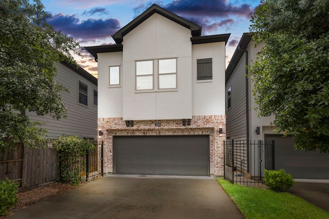 contemporary home featuring stucco siding, fence, brick siding, and a garage