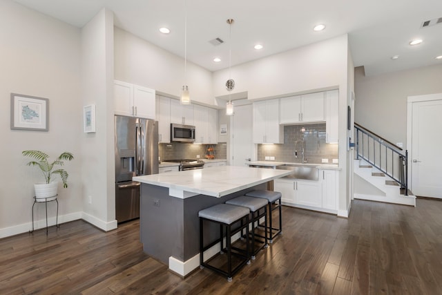kitchen featuring a sink, a center island, white cabinetry, appliances with stainless steel finishes, and dark wood finished floors