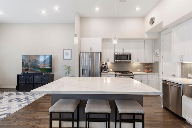 kitchen featuring appliances with stainless steel finishes, a breakfast bar area, white cabinets, and backsplash