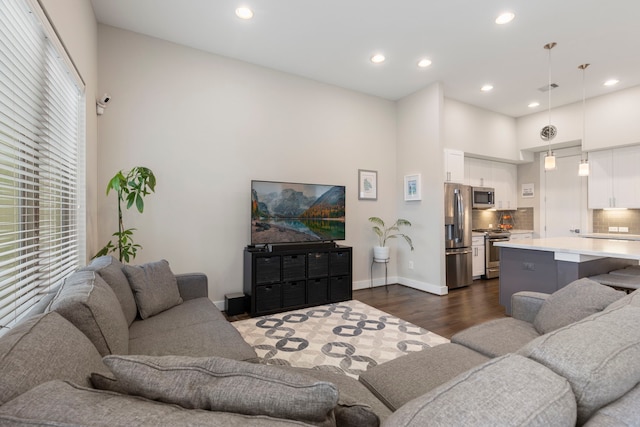 living room featuring dark wood-type flooring, recessed lighting, a high ceiling, and baseboards