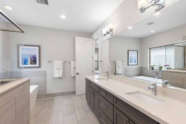 bathroom featuring visible vents, a washtub, and a sink