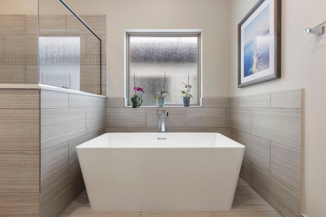 full bathroom with tile patterned flooring, tile walls, and a soaking tub