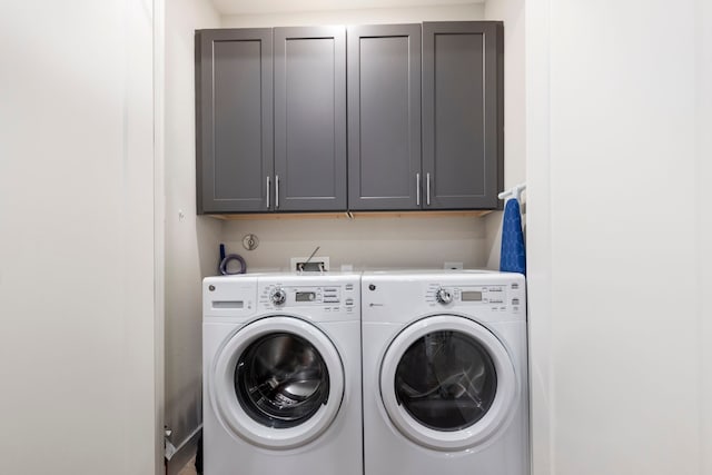clothes washing area with washing machine and dryer and cabinet space