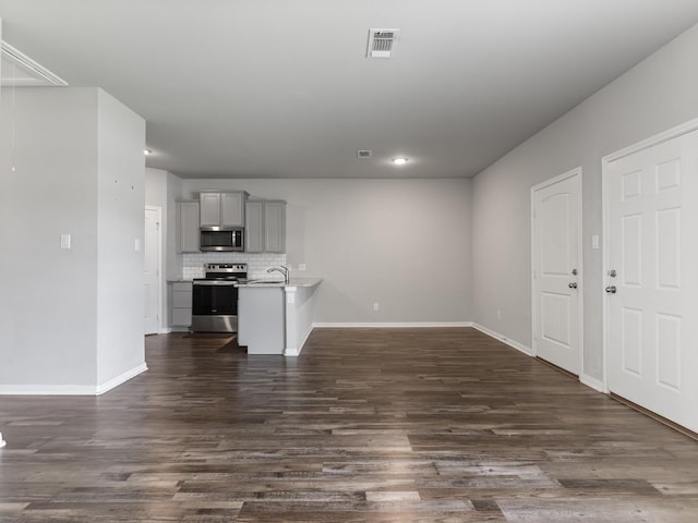 unfurnished living room with baseboards, visible vents, and dark wood-type flooring