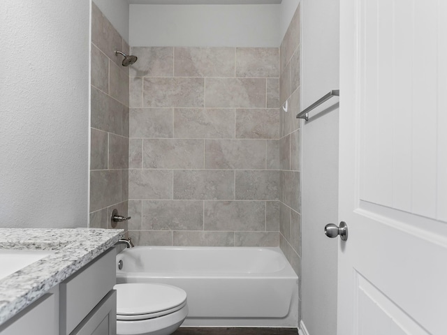 bathroom featuring toilet, a textured wall, bathtub / shower combination, and vanity
