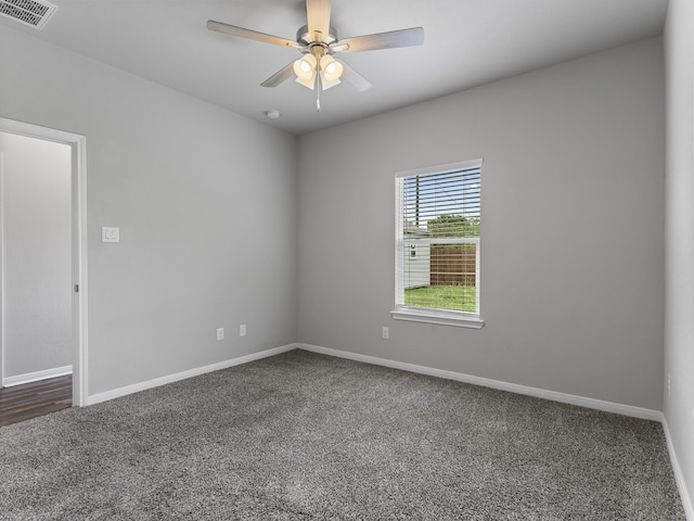 2921 4th St, Bay City, TX 77414 - spare room featuring dark colored carpet, baseboards, and a ceiling fan