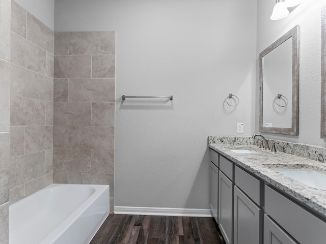 bathroom featuring double vanity, wood finished floors, baseboards, and a sink