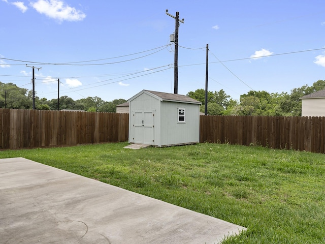 view of yard featuring a patio, a fenced backyard, a shed, and an outbuilding
