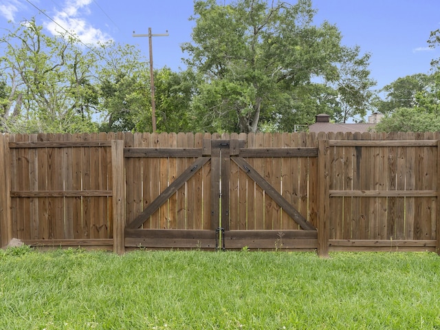 view of gate featuring fence and a yard