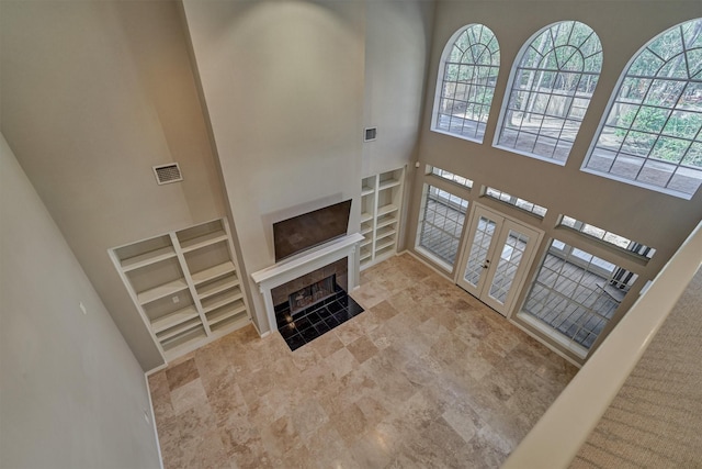 foyer with a towering ceiling, visible vents, a tiled fireplace, and plenty of natural light