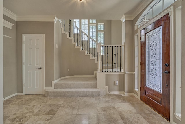 foyer with ornamental molding, stairs, and baseboards