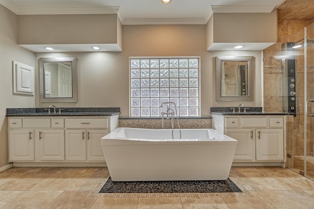 bathroom with ornamental molding, a shower stall, a freestanding bath, and two vanities