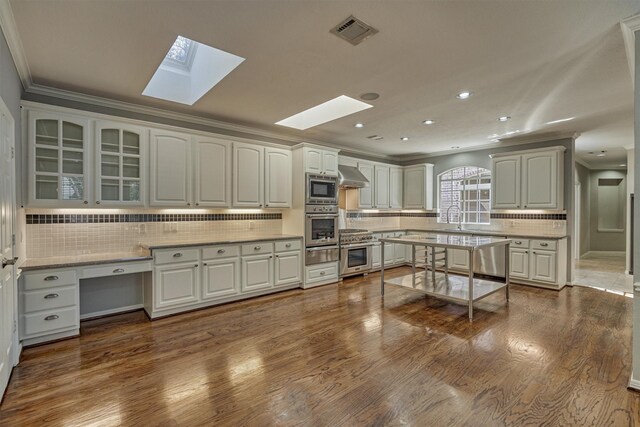 kitchen with a skylight, decorative backsplash, appliances with stainless steel finishes, a warming drawer, and ornamental molding