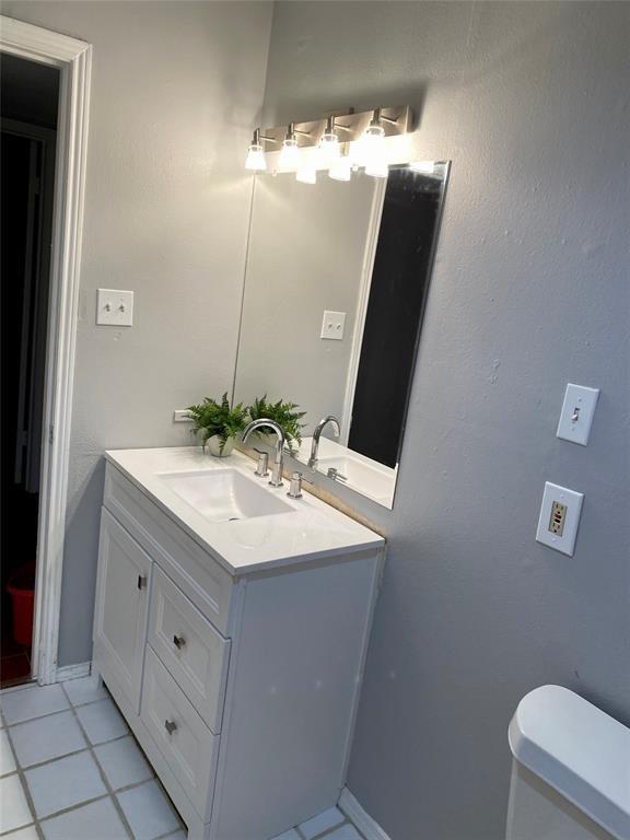 bathroom with toilet, tile patterned floors, vanity, and baseboards