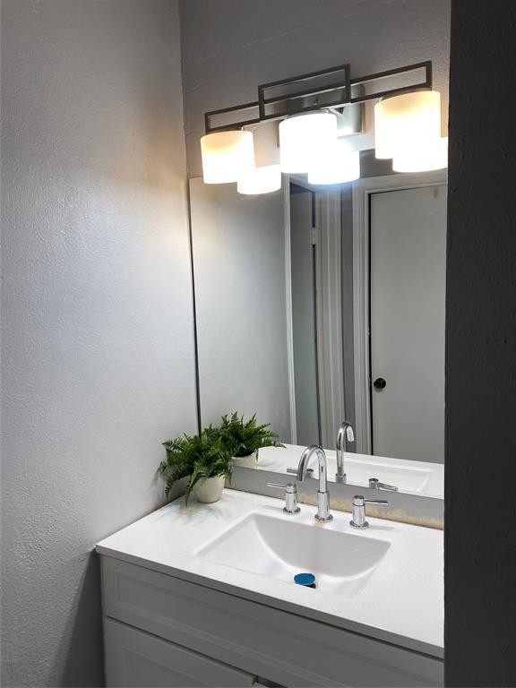bathroom with a textured wall and vanity