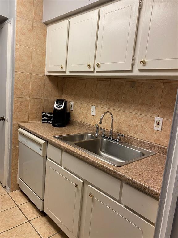 kitchen with a sink, dishwasher, white cabinetry, and tasteful backsplash