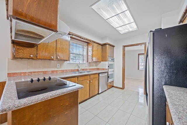 7718 Pella Dr, Houston, TX 77036 - kitchen with light tile patterned floors, brown cabinets, a sink, stainless steel appliances, and light countertops