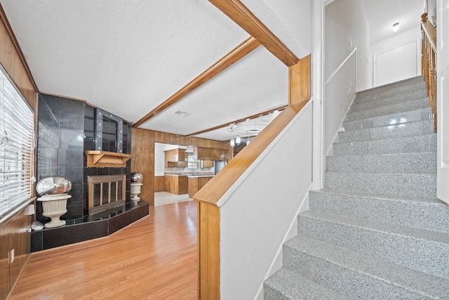 7718 Pella Dr, Houston, TX 77036 - staircase with visible vents, wood walls, wood finished floors, and a fireplace