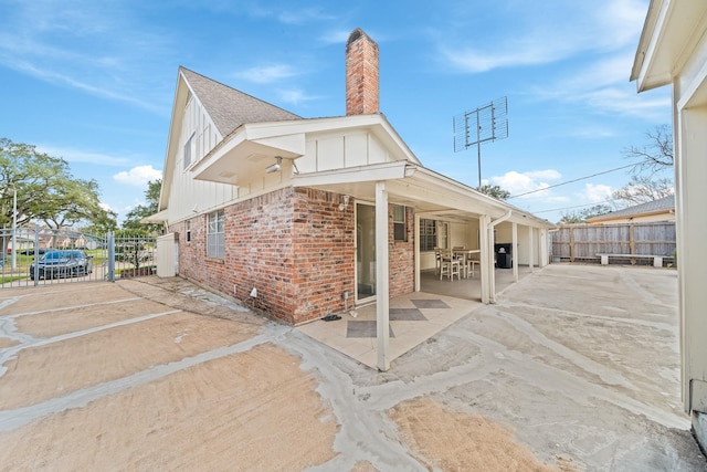 7718 Pella Dr, Houston, TX 77036 - back of house featuring board and batten siding, a chimney, a patio area, fence, and brick siding
