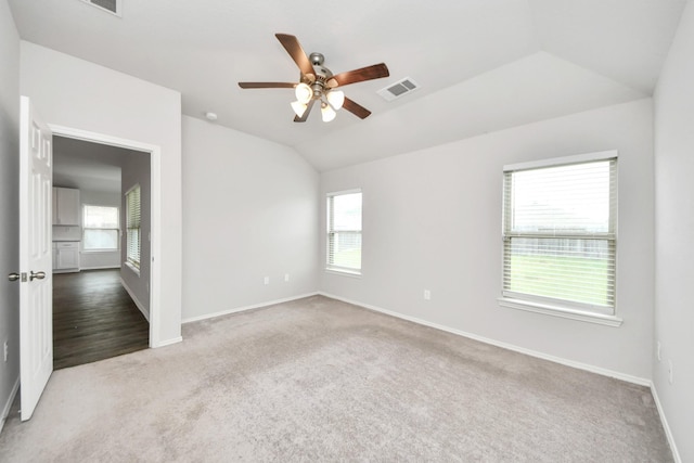 spare room with lofted ceiling, carpet flooring, visible vents, baseboards, and a ceiling fan