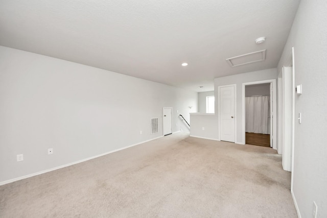 unfurnished room featuring recessed lighting, light colored carpet, attic access, baseboards, and visible vents