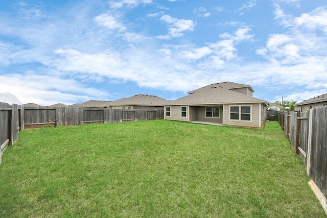 rear view of house featuring a yard and a fenced backyard