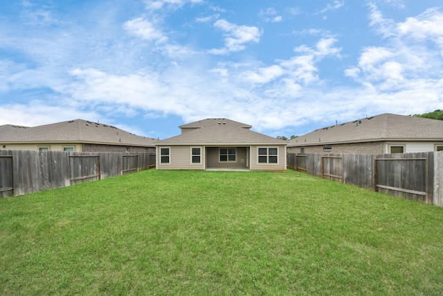 back of house with a fenced backyard and a yard