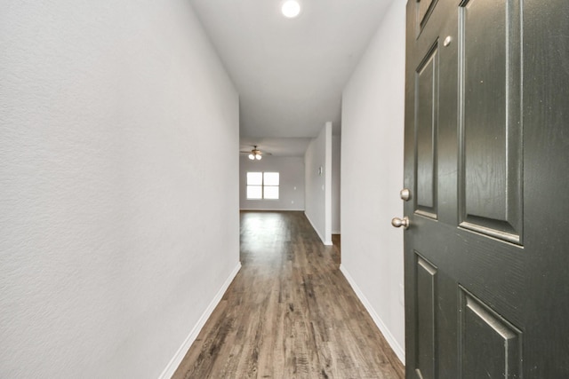 corridor with wood finished floors and baseboards
