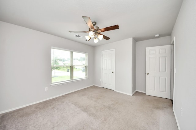 unfurnished bedroom featuring visible vents, baseboards, a ceiling fan, and light carpet