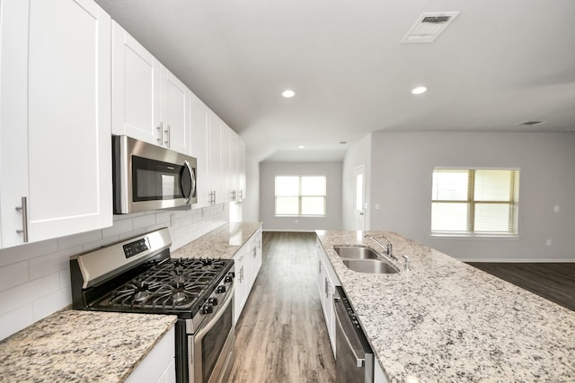 kitchen with light stone counters, a sink, appliances with stainless steel finishes, visible vents, and wood finished floors
