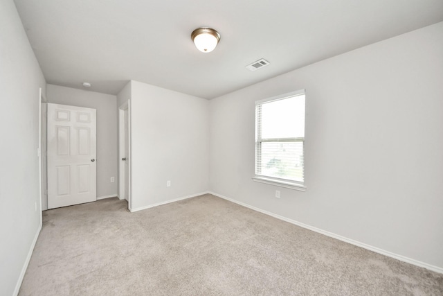 unfurnished room with light colored carpet, visible vents, and baseboards