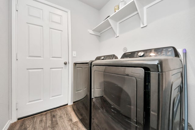 clothes washing area featuring separate washer and dryer, wood finished floors, and laundry area