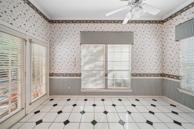 empty room featuring ornamental molding, a wainscoted wall, ceiling fan, and wallpapered walls