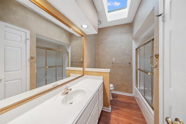 full bath featuring vanity, toilet, baseboards, a skylight, and wood finished floors